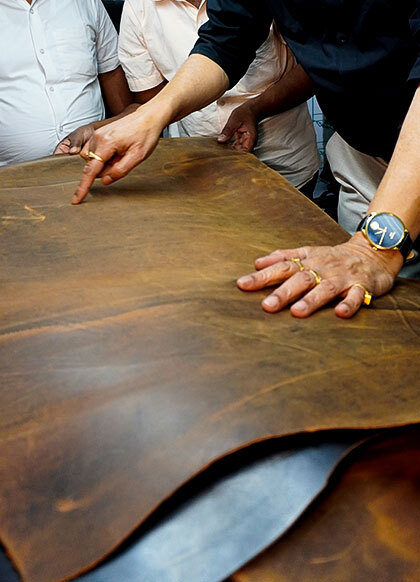 Skilled artisans inspecting and hand finishing premium leather material for high quality bag manufacturing and OEM production in India